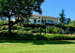 French Farmhouse villa in distance, wide green lawn in the foreground.