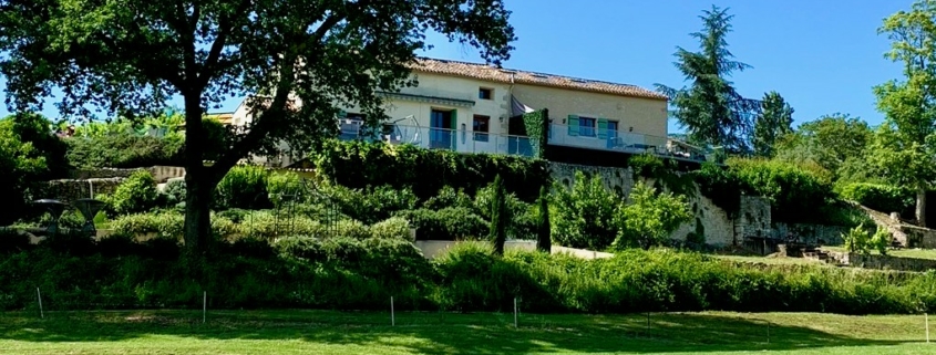 French Farmhouse villa in distance, wide green lawn in the foreground.