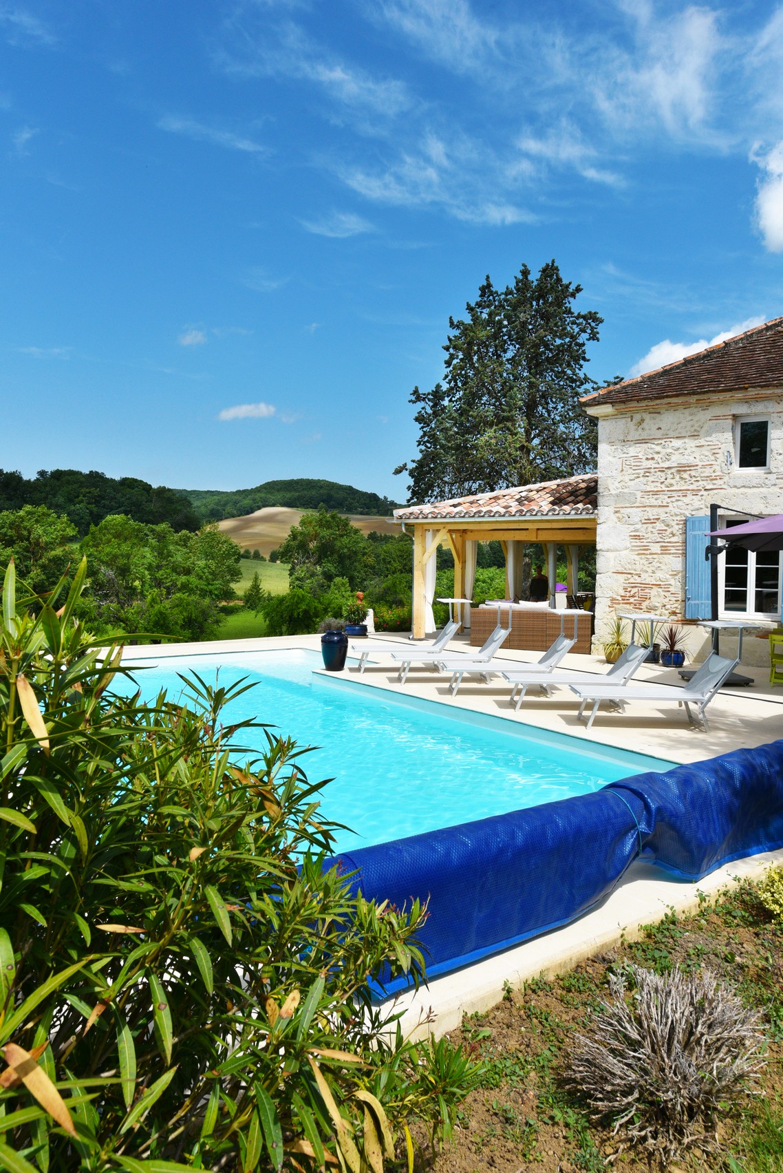 French Manoir holiday rental, white stone walls with blue shutters and pigieonnere tower, green lawn and shrubs