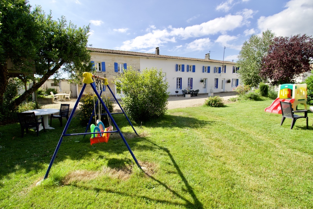 La Bigorre Farmhouse showing the house in the distance and the garden and kids swings in the foreground