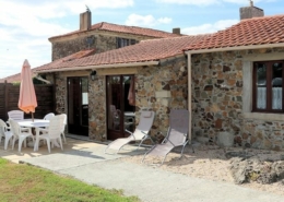 View of French gite with terracotta tiled roof and traditional stone walls. Patio area with sunloungers and table & chairs