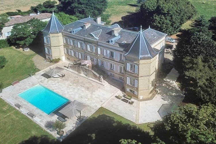 Aerial view of French Chateau with two turrets and view of swimming pool.